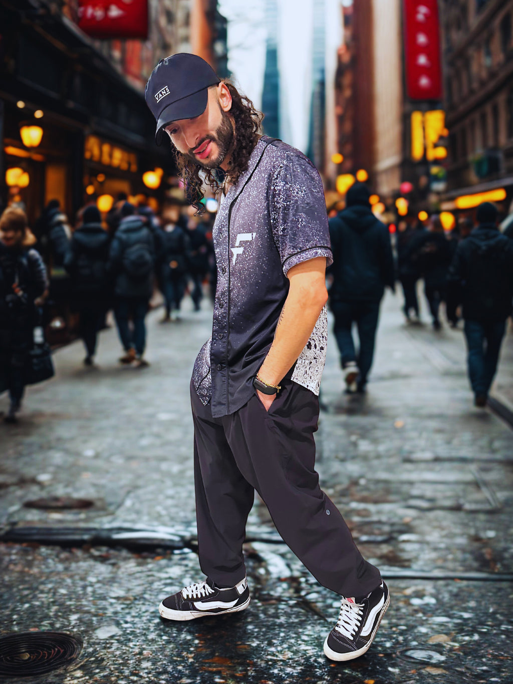 Man walking on a city street wearing a dark cap, patterned shirt, and black pants. Wearing stylish rave jersey. Comfort fit and made for raves, gym wear, street wear and more. 

